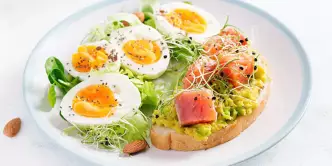 Alimentos ricos em vitamina E: Leguminosas, brócolis, frutas e salmão colocados sobre um piso de cimento preto