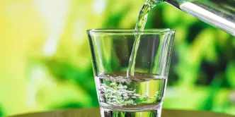 Um copo de vidro com água pronto para ser bebido em um fundo verde