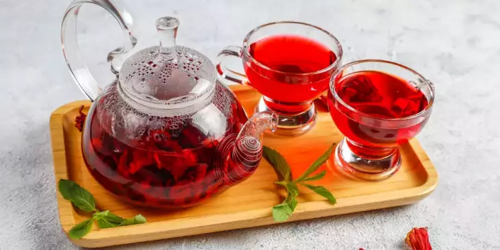 chá de hibisco quente em uma caneca de vidro e bule de vidro