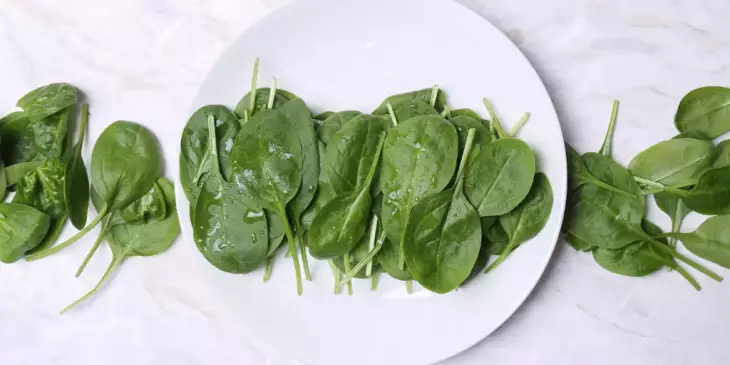 Uma mesa com folhas de espinafre alinhadas verticalmente