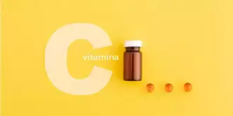 letra C branca com um vidro com várias cápsulas de vitamina C ao redor