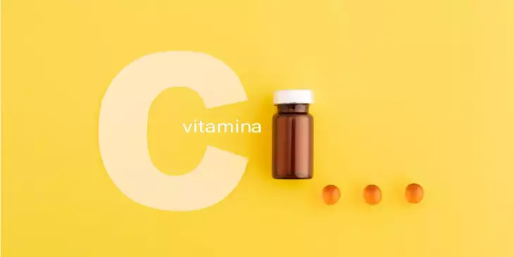 letra C branca com um vidro com várias cápsulas de vitamina C ao redor